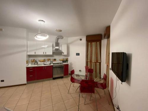 eine Küche mit roten Schränken, einem Tisch und einem TV in der Unterkunft CV Martesana Gorgonzola 4 in Gorgonzola