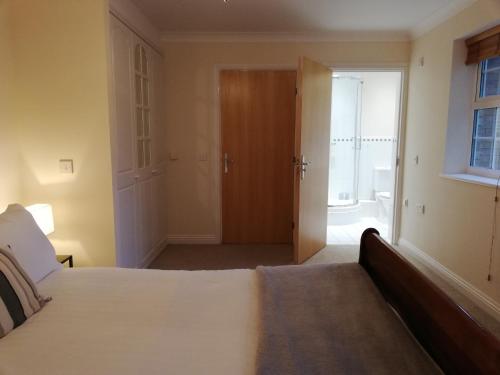 a bedroom with a bed and a door to a bathroom at Brand New 2 bed in one of Newbury oldest buildings in Newbury