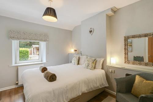a bedroom with a large white bed and a chair at Lilac Cottage in Parkend