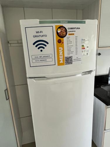 a white refrigerator with a sign on top of it at Cobertura Climatizada com Suíte à 2km do Aeroporto de Salvador e Praias in Lauro de Freitas