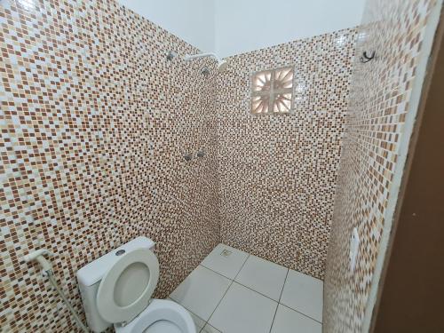 La salle de bains est pourvue de toilettes et d'un mur carrelé. dans l'établissement Casa com piscina 300 M Broadway Canoa quebrada, à Canoa Quebrada