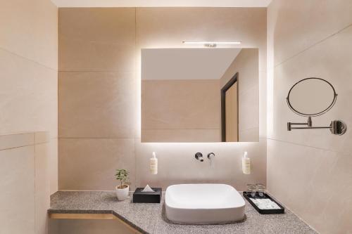 een badkamer met een wit toilet en een spiegel bij Lemon Tree Hotel, Haridwar in Haridwār