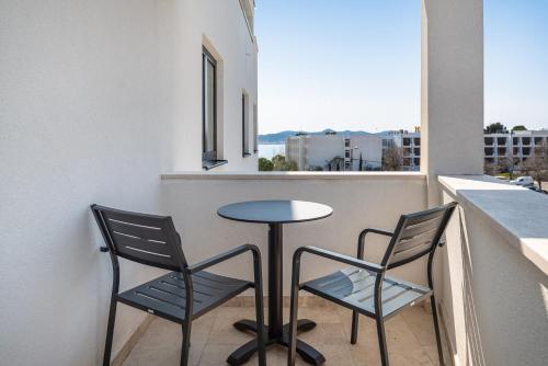 a small table and two chairs on a balcony with a window at Miramare Hotel in Zadar