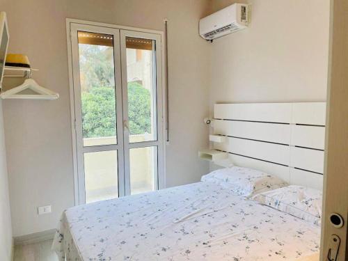 a white bedroom with a bed and a window at 50 passi dal mare in Lampedusa