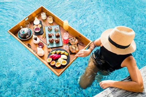 una persona en un barco con comida en una piscina en Alia Luxury Suites and Spa en Haraki