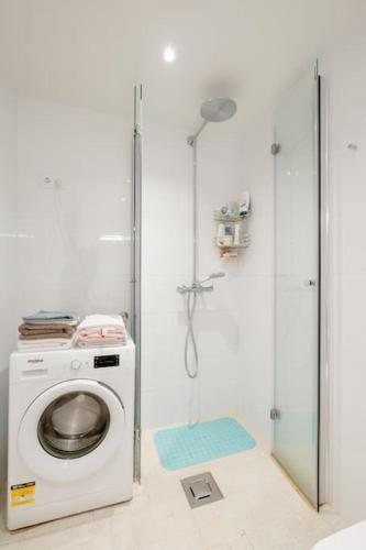 a washing machine in a bathroom with a shower at Fabulous Morden Apartment in Helsinki in Helsinki