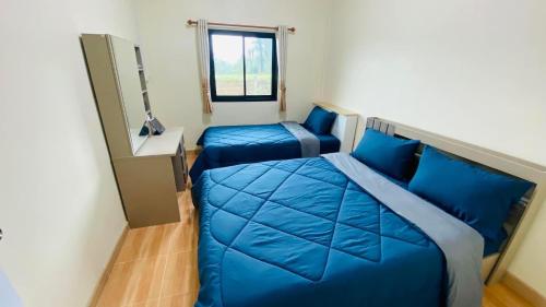 a bedroom with two blue beds and a window at ภูระเริงวิลล่า วังน้ำเขียว Phu Raroeng Villa in Ban Khlong Ki