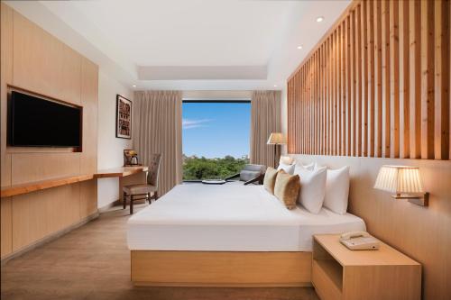 een hotelkamer met een bed en een televisie bij Lemon Tree Hotel, Haridwar in Haridwār