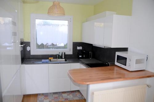 une cuisine avec des placards blancs et un four micro-ondes sur un comptoir dans l'établissement CHARMANT APPARTEMENT en BRETAGNE, PROCHE La BAULE et GRANDE PLAGE, 4 ETOILES, à Batz-sur-Mer