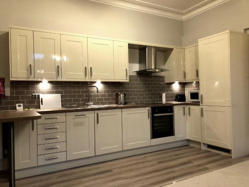 a white kitchen with white cabinets and appliances at A spacious 1 bedroom in an historic building in Newbury