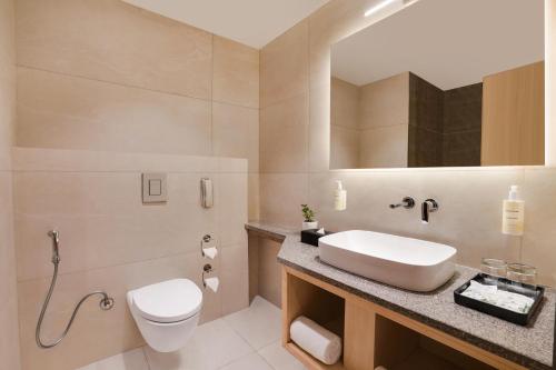 a bathroom with a sink and a toilet and a mirror at Lemon Tree Hotel, Haridwar in Haridwār