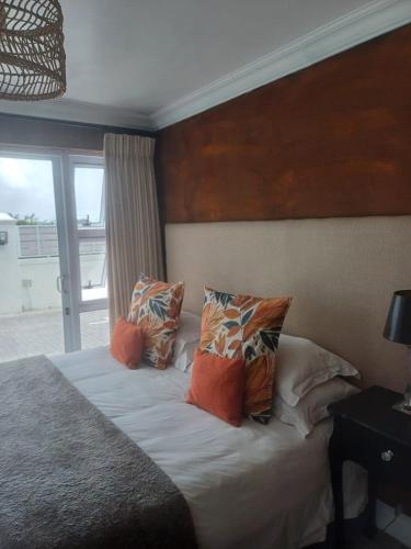 a bedroom with a bed with pillows and a window at Thyme Wellness Spa and Guesthouse in Cape Town