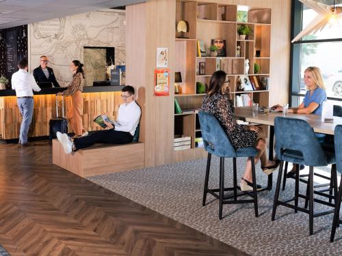a group of people sitting at a counter in a restaurant at Mercure Valenciennes Centre in Valenciennes