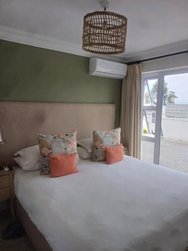 a bedroom with a white bed with pillows and a window at Thyme Wellness Spa and Guesthouse in Cape Town
