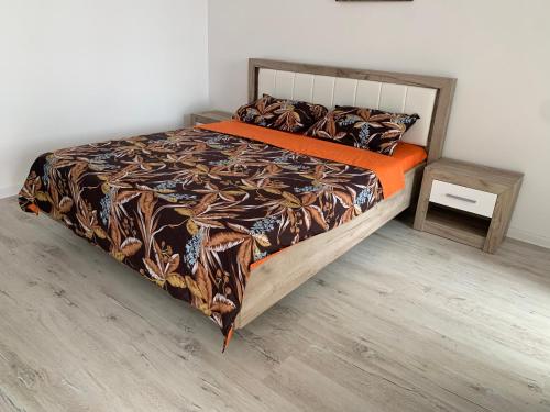 ein Bett mit einer orangefarbenen Bettdecke und einem Beistelltisch in der Unterkunft Residence Tineretului in Roşu