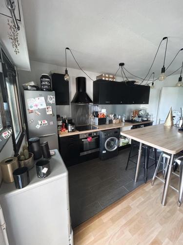 eine Küche mit schwarzen Schränken, einem Tisch und einem Kühlschrank in der Unterkunft Appartement agréable 1 chambre in Mérignac