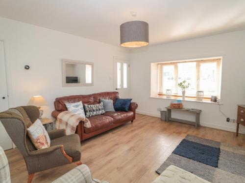 una sala de estar con un sofá de cuero marrón y sillas en 2 Cross View en Berwick-Upon-Tweed