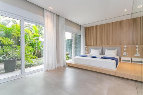 um quarto com uma cama grande e janelas grandes em Garden | Churrasqueira | Piscina Condomínio #JA27 em Florianópolis