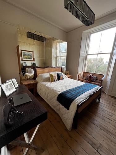 a bedroom with a bed and a table and windows at Edradour in St. Andrews
