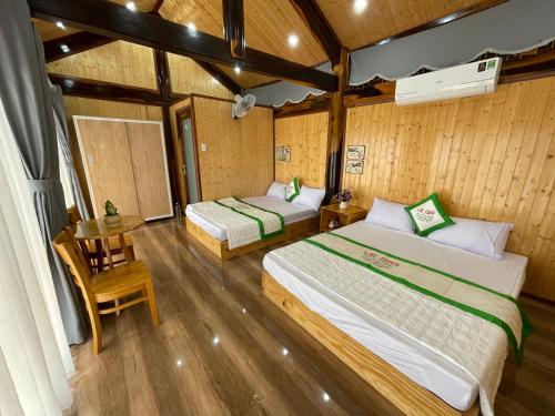 two beds in a room with wooden walls and wooden floors at Homestay Lê Gia in Xuyên Mộc