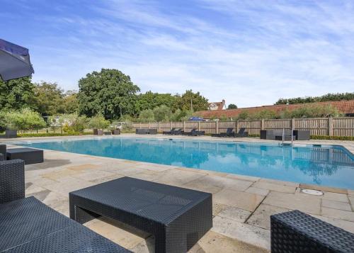 a swimming pool with a black table and chairs at Alder Country Park in North Walsham