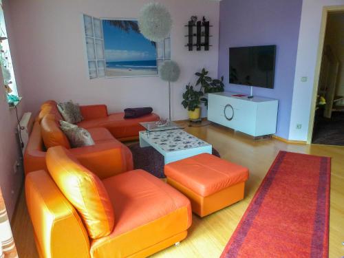 ein Wohnzimmer mit orangefarbenen Möbeln und einem Flachbild-TV in der Unterkunft Holiday Home Bellevue by Interhome in Bad Sachsa