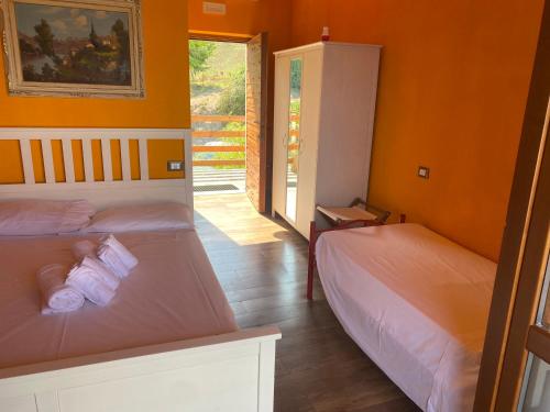 Duas camas num quarto com paredes cor de laranja em Lo Scoiattolo Country House em Montorio al Vomano