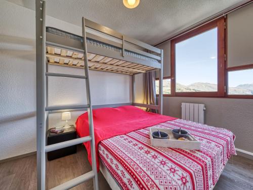une chambre avec un lit superposé avec un couvre-lit rouge dans l'établissement Apartment Vostok Zodiaque-92 by Interhome, au Corbier