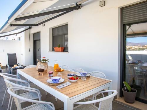 Una mesa de madera en un patio con sillas. en Apartment Maroma by Interhome, en Torre del Mar