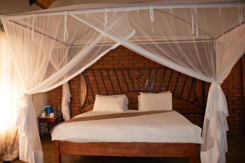 1 dormitorio con cama con dosel y cortinas blancas en iroCK Lodge en Victoria Falls