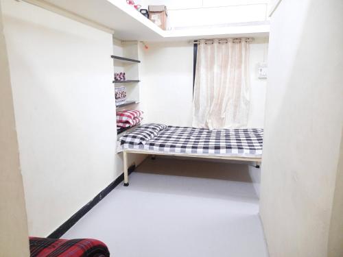 a small bed in a room with a window at Shriguru Guest House Akkalkot in Akalkot