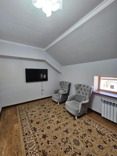 een woonkamer met 2 stoelen en een flatscreen-tv bij ESALU Guest House ЭСАЛУ in Privokzalʼnoye