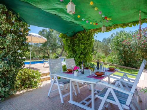 une table et des chaises blanches sous un parasol vert dans l'établissement Villa Sa Teulada by Interhome, à Santa Margalida