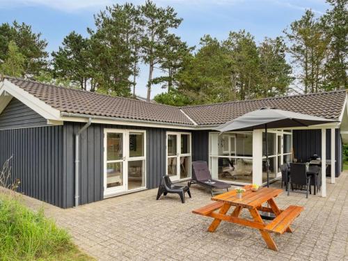 uma casa com um pátio com uma mesa e cadeiras em Holiday Home Thjodulf - 300m from the sea in Djursland and Mols by Interhome em Knebel