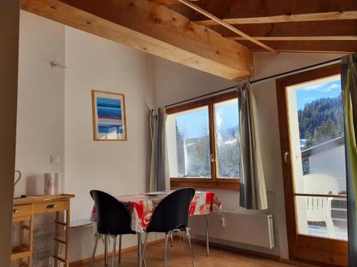 comedor con mesa, sillas y ventanas en Apartment Casa Fadail Seura 21 by Interhome, en Lenzerheide