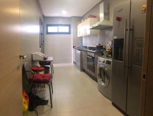 a kitchen with a washing machine and a table and chairs at OCEAN VIEW, Prestigia Plage des Nations in Sidi Bouqnadel