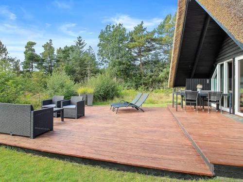 eine Holzterrasse mit Stühlen und Tischen auf einem Haus in der Unterkunft Holiday Home Awenasa - 4-1km from the sea in Western Jutland by Interhome in Nørre Nebel