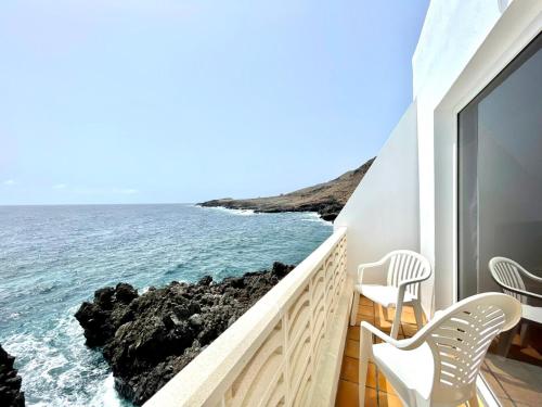 Un balcón con sillas y vistas al océano. en Apartamento vista mar, a escasos metros de la playa, en Tamaduste