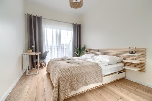 a white bedroom with a bed and a window at Lovely SPA 31 in Dziwnów