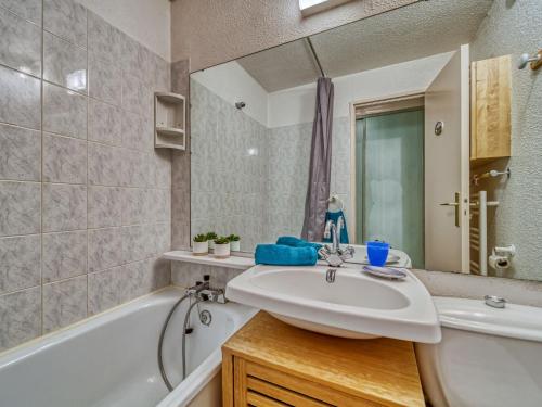 une salle de bain avec un lavabo, une baignoire et un miroir dans l'établissement Studio Lunik Orion-49 by Interhome, au Corbier