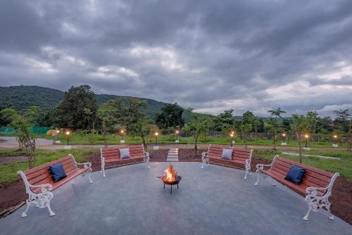 a group of benches sitting around a fire pit at SaffronStays Ivory Mansion in Pen
