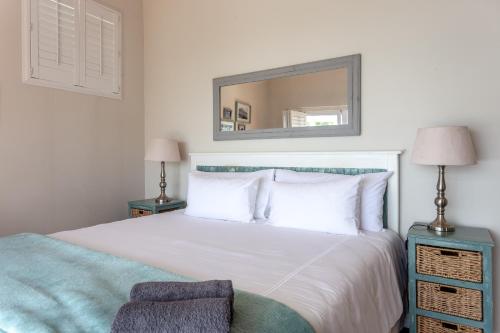 a bedroom with a white bed and a mirror at Paradise Views Vacation Home in Cape Town