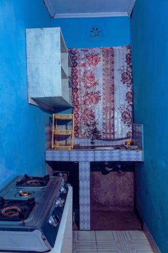 a kitchen with a stove and a blue wall at Amadius in Lodwar