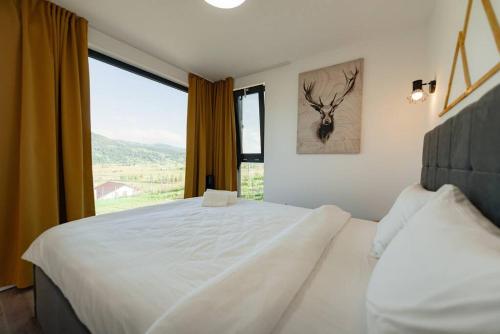 a bedroom with a large white bed with a window at Cozy Cube - tiny house in Şarul Dornei