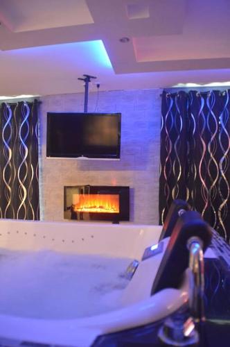 Elle comprend un salon avec une cheminée et une télévision murale. dans l'établissement Love Room insolite Erotika, à Le Chesne