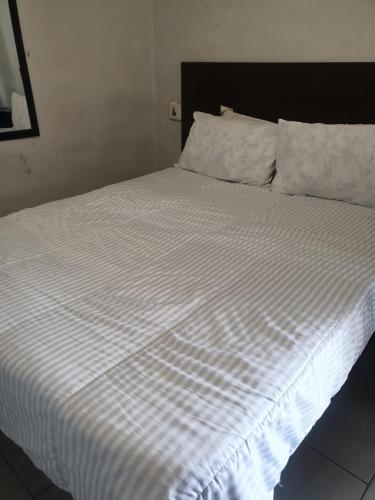 a bed with a white striped sheets and pillows at liam travel inn in Nelspruit