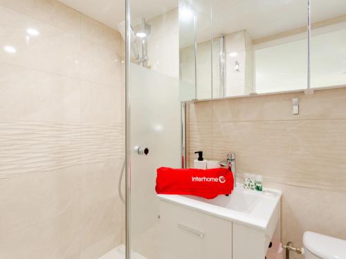 La salle de bains est pourvue d'une douche et d'un lavabo avec une serviette rouge. dans l'établissement Apartment Mirabeau by Interhome, à Deauville