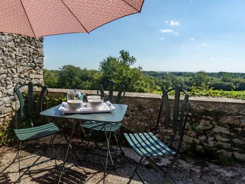 einen Tisch mit 2 Stühlen und einem Sonnenschirm auf einer Terrasse in der Unterkunft Holiday Home by Interhome in Agon Coutainville