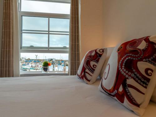 a bed with a window with a view of a marina at Apartment Lighthouse View by Interhome in Mevagissey