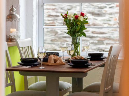 a table with a vase of flowers and wine glasses at Apartment Lighthouse View by Interhome in Mevagissey
